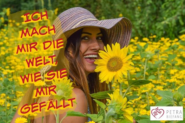 Lachende Frau mit Sonnenhut mitten eines sonnigen Blumenfeldes, umgeben von gelben Sonnenblumen, mit Zitat: Ich mach mir die Welt, wie sie mir gefällt - Ausdruck von Selbstwert, Lebensfreude, Lebendigkeit und innerer Freiheit - Coaching by Petra Biefang