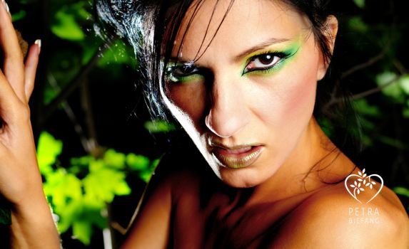 Frau mit intensivem Blick und grünem Lidschatten vor Pflanzen - Sinnbild für Selbstliebe und die wilde Frau im Frauenkreis